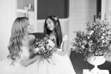 Düğün için. Evdeki gibi beyaz stüdyo içinde, güzel elbiseli gelin kanepede oturuyor. Modaya uygun bir düğün fotoğrafı. Genç, beyaz, esmer bir model, gelin gibi.