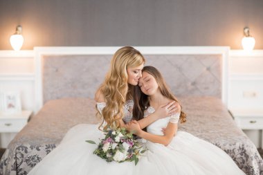 Düğün için. Evdeki gibi beyaz stüdyo içinde, güzel elbiseli gelin kanepede oturuyor. Modaya uygun bir düğün fotoğrafı. Genç, beyaz, esmer bir model, gelin gibi.