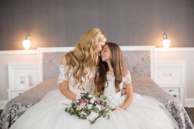 Düğün için. Evdeki gibi beyaz stüdyo içinde, güzel elbiseli gelin kanepede oturuyor. Modaya uygun bir düğün fotoğrafı. Genç, beyaz, esmer bir model, gelin gibi.