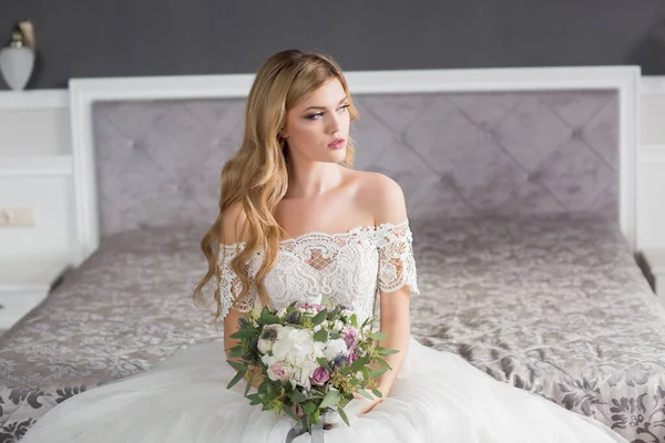 結婚式 自宅のような白いスタジオのインテリアでソファの上に座って美しいドレスで花嫁 トレンドの結婚式のスタイルはフル長さで撮影 若いです魅力的な白人ブルネットモデルのような花嫁 — ストック写真