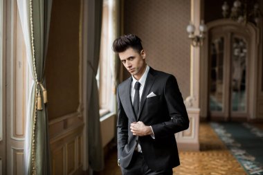 Güzel bir odada yeni takım elbiseli yakışıklı bir erkek.