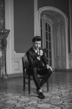 Güzel bir odada yeni takım elbiseli yakışıklı bir erkek.