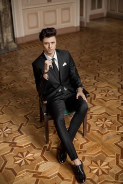 Güzel bir odada yeni takım elbiseli yakışıklı bir erkek.