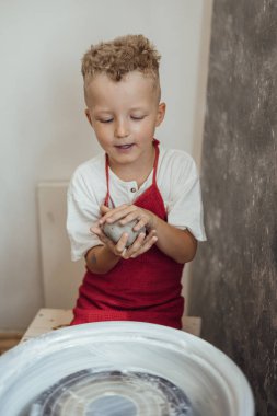 Çömlek atölyesinde, el sanatları ve kil sanatı, çocuk yaratıcı aktiviteler, sanat eğitimi gibi konularda modellik yapan sevimli bir çocuk.