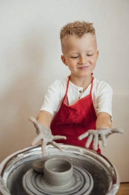 Çömlek atölyesinde, el sanatları ve kil sanatı, çocuk yaratıcı aktiviteler, sanat eğitimi gibi konularda modellik yapan sevimli bir çocuk.