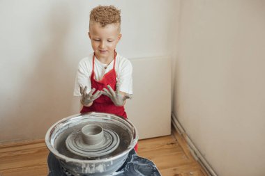 Çömlek atölyesinde, el sanatları ve kil sanatı, çocuk yaratıcı aktiviteler, sanat eğitimi gibi konularda modellik yapan sevimli bir çocuk.