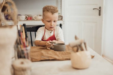 Çömlek atölyesinde, el sanatları ve kil sanatı, çocuk yaratıcı aktiviteler, sanat eğitimi gibi konularda modellik yapan sevimli bir çocuk.