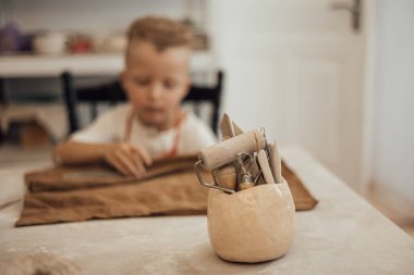 Çömlek atölyesinde, el sanatları ve kil sanatı, çocuk yaratıcı aktiviteler, sanat eğitimi gibi konularda modellik yapan sevimli bir çocuk.