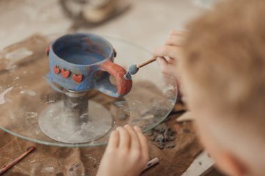Çömlek atölyesinde, el sanatları ve kil sanatı, çocuk yaratıcı aktiviteler, sanat eğitimi gibi konularda modellik yapan sevimli bir çocuk.
