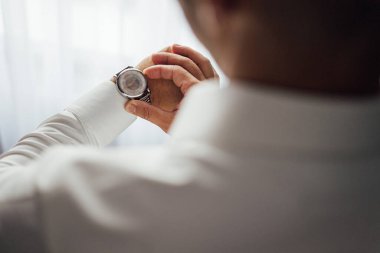 İş adamı kol saatini kontrol ediyor, saati eline alıyor, damat düğün töreninden önce hazırlanıyor.