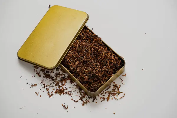 Beyaz arka planı olan altın bir kutuda kaliteli tütün.
