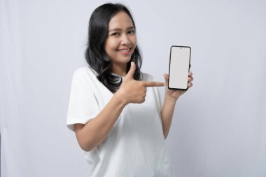Gülümseyen ve boş ekranlı bir telefonu işaret eden bir kadın.