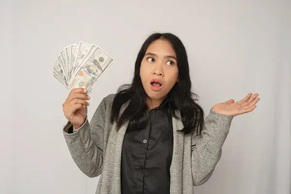 Şaşırmış bir ifadeyle bir yığın para tutan ve elini uzatan bir kadın.