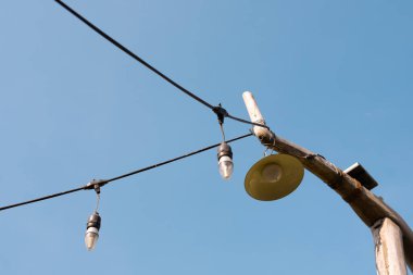 İki ampulü yanan ve bir feneri bağlı olan bir ışık dizisini tutan tahta bir direk.