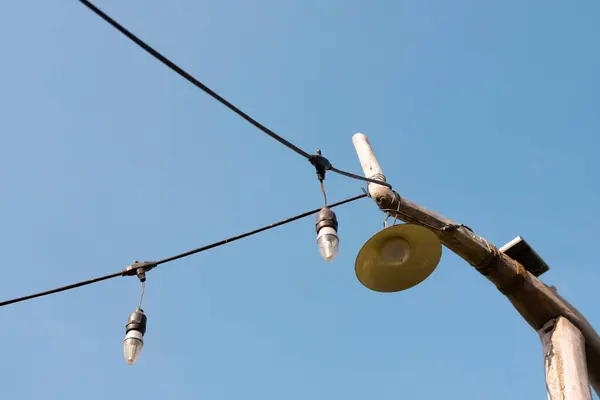 İki ampulü yanan ve bir feneri bağlı olan bir ışık dizisini tutan tahta bir direk.