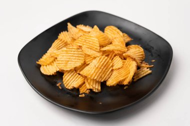 Siyah tabakta bir yığın patates cipsi.