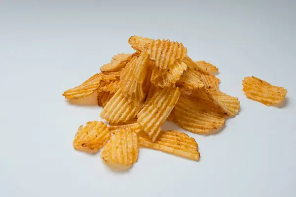 Beyaz bir yüzeye dağılmış bir patates cipsi yığını.