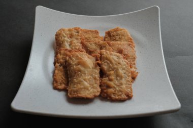 crispy flour fried tempeh which is served on a plate. clipart