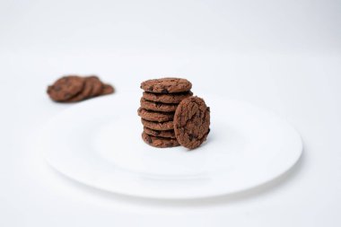 Beyaz bir tabakta duran çikolata parçalı kurabiyeler.