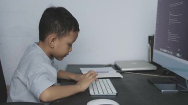 Bir çocuk ödevlerini bilgisayarın önünde klavyesini yazarak öğreniyor.