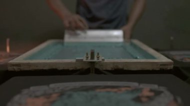 Tekstil fabrikası süreci, baskı çerçevesi, tekstil ve kumaş baskı sürecinin içine cam sileceği iten adam.