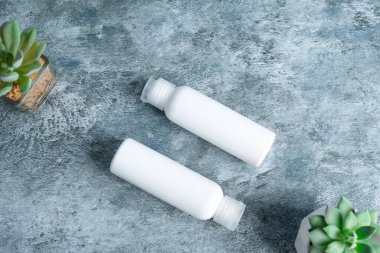 Beton yüzeyde iki beyaz losyon şişesi düzlüğü, güzellik tasarımı sunumu için harika..