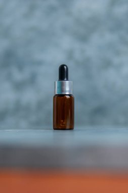 Çimento yüzeyi üzerinde koyu kahverengi serum şişesi, damlalık şişesi, güzellik, spa ve sağlık konsepti