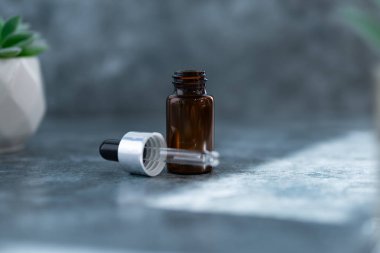 Çimento yüzeyi üzerinde koyu kahverengi serum şişesi, damlalık şişesi, güzellik, spa ve sağlık konsepti