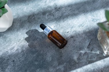 Çimento yüzeyi üzerinde koyu kahverengi serum şişesi, damlalık şişesi, güzellik, spa ve sağlık konsepti