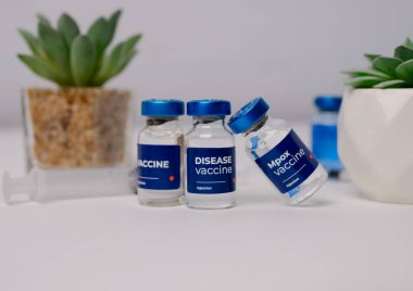 Birkaç aşı ve bir klinik odasındaki masanın üzerinde süs çiçekleri olan bir şırınga. sağlık ve tıbbi kavramlar