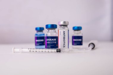 Antibiyotikler ve klinik odasındaki masanın üstünde süs çiçekleri olan sıvı aşılar. sağlık ve tıbbi kavramlar