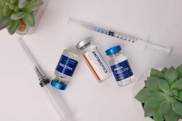 Bazı aşılar ve bir klinik odasındaki masanın üzerinde süs çiçekleri olan bir şırınga. sağlık ve tıbbi kavramlar