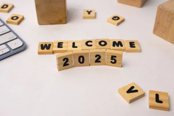 Hoş geldin 2025 beyaz bir masada tahta bloklarla yazılmış.