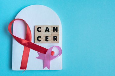 Kanser harflerine karşı pembe ve kırmızı kanser kurdeleleriyle savaş. Dünya Kanser Günü. kanser arka planı