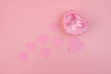 Pembe kurdeleli kalp şeklinde bir hediye kutusu birkaç küçük pembe kalbin arasında duruyor. Sevgililer günü hediye konsepti