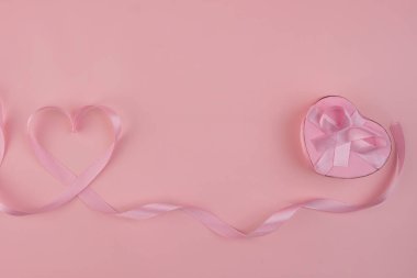 Pembe kurdele, kalp şeklinde bir hediye kutusunun yanında pembe kurdeleli bir kalp şekli oluşturuyor. Valentine arkaplan kavramı