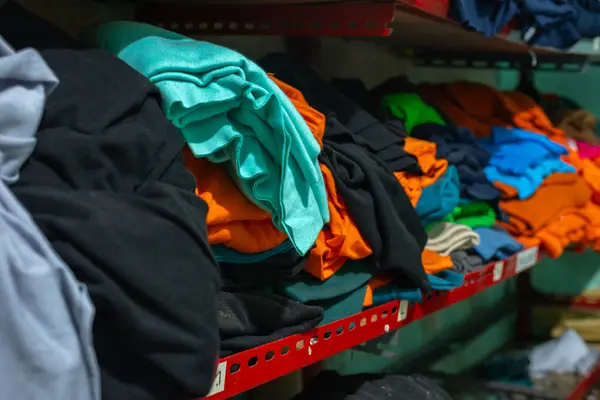 Raflara konmuş katlanmış ve dağınık kumaşlar.