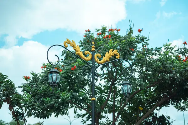 Süslemeli bir sokak lambası Çiçekli bir ağacın altında duruyor
