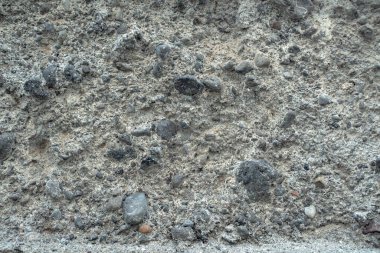 Sert beton yüzey ve gömülü taşlar. Kaba kum, çakıl ve çimentodan yapılmış kaba bir yüzeye sahip bir beton dokusu..