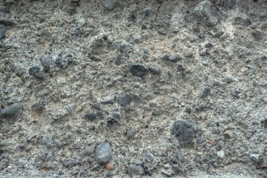 Sert beton yüzey ve gömülü taşlar. Kaba kum, çakıl ve çimentodan yapılmış kaba bir yüzeye sahip bir beton dokusu..
