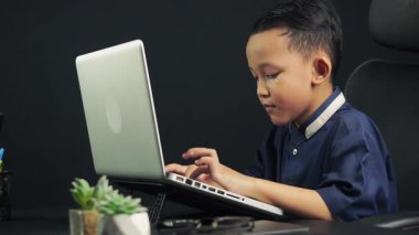 Bir çocuk ödevlerini yapmak için dizüstü bilgisayar kullanmayı öğreniyor. teknoloji eğitimi kavramı