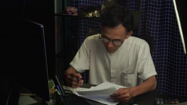 Bir muhasebeci bilgisayarın önünde mali bir belgeyi analiz ederken, belgeyi incelerken kafası karışmış bir ifade gösterir. iş ve mali kavramlar.