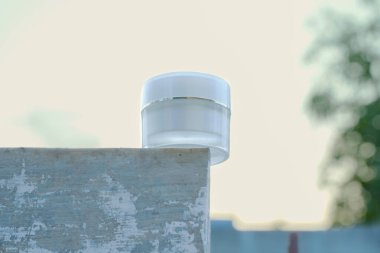 Çimento bloğunda duran beyaz krema kavanozu.