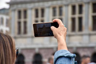 Antwerp, Belçika 'daki Silvius Bravo anıtının fotoğraflarını çeken, dokunmatik ekranlı akıllı telefon cihazı olan bir kadın turistin ellerinin detaylı görüntüsü.
