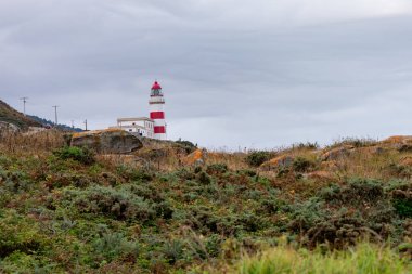 Cabo Silleiro deniz feneri. Kayalık dağ rehberlerinde kırmızı çizgileri olan denizciler.