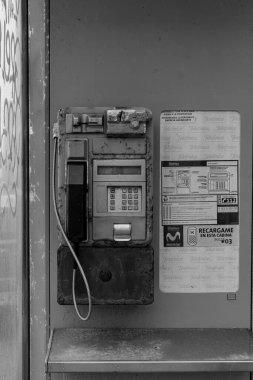 Eski bozuk para işleten telefonu, şirket imzası ve arama fiyatları olan bir kabin.