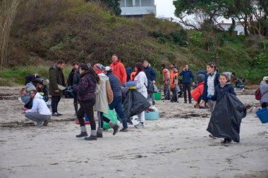 Nigran, İspanya; Ocak 09.2024; Çok sayıda gönüllü, huni, süzgeç, eldiven gibi temel araçlar kullanarak bir tekneye düşen plastik topakları toplamak için Galiçya plajlarına gitti.