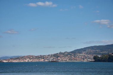 Playa America kıyılarında küçük evler, turkuaz mavi bir deniz ve Nigran, Pontevedra, İspanya 'da açık bir gökyüzü.