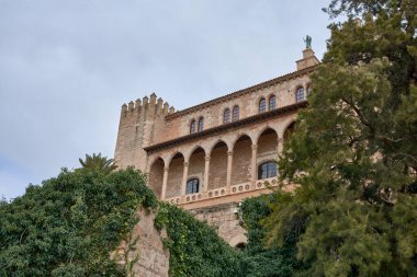 İspanya, Balearic Adaları, Palma de Mallorca 'daki bazı ağaçlarla La Almudaina Kraliyet Sarayı' nın aşağısından görüntü