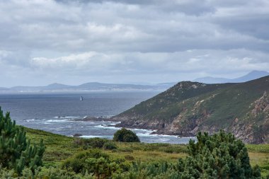 Ons Adası 'ndaki Buraco do Inferno' dan muhteşem bir manzara, mavi bir deniz, kayalık uçurumlar, Pontevedra haliçleri ve Pontevedra, Galiçya, İspanya 'da dağınık bulutlarla dolu bir yaz gökyüzü.